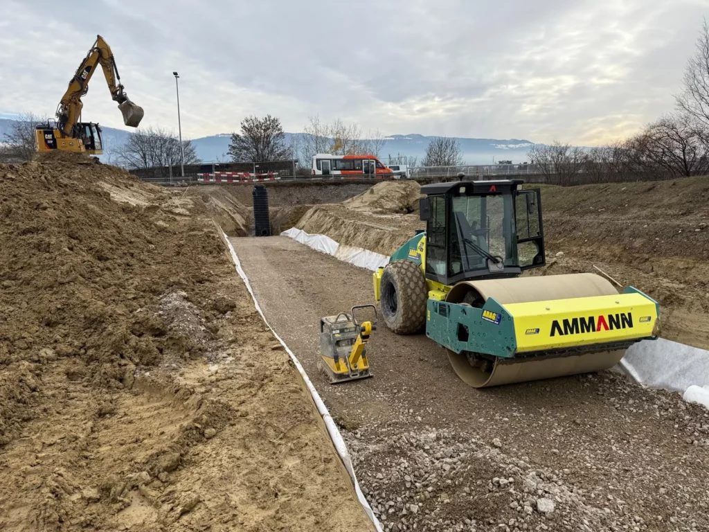 Compacteur et pelle mécanique sur le chantier STI Cherpines à Plan-les-Ouates